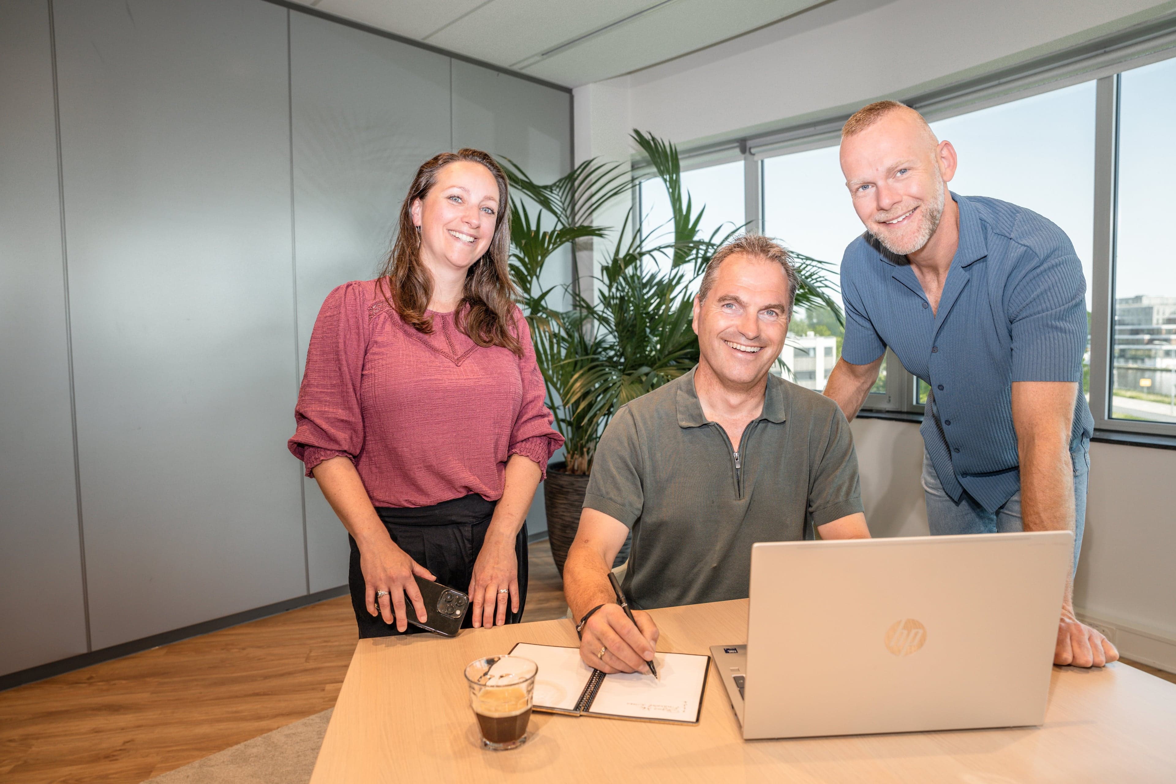 Drie werknemers op kantoor achter laptop