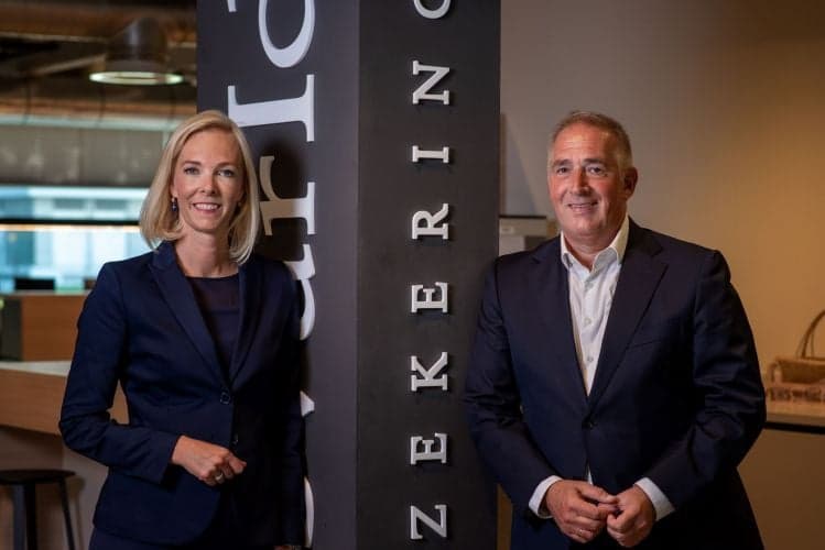 Femke en Peter van Turien & Co poseren in een kantooromgeving naast een zuil