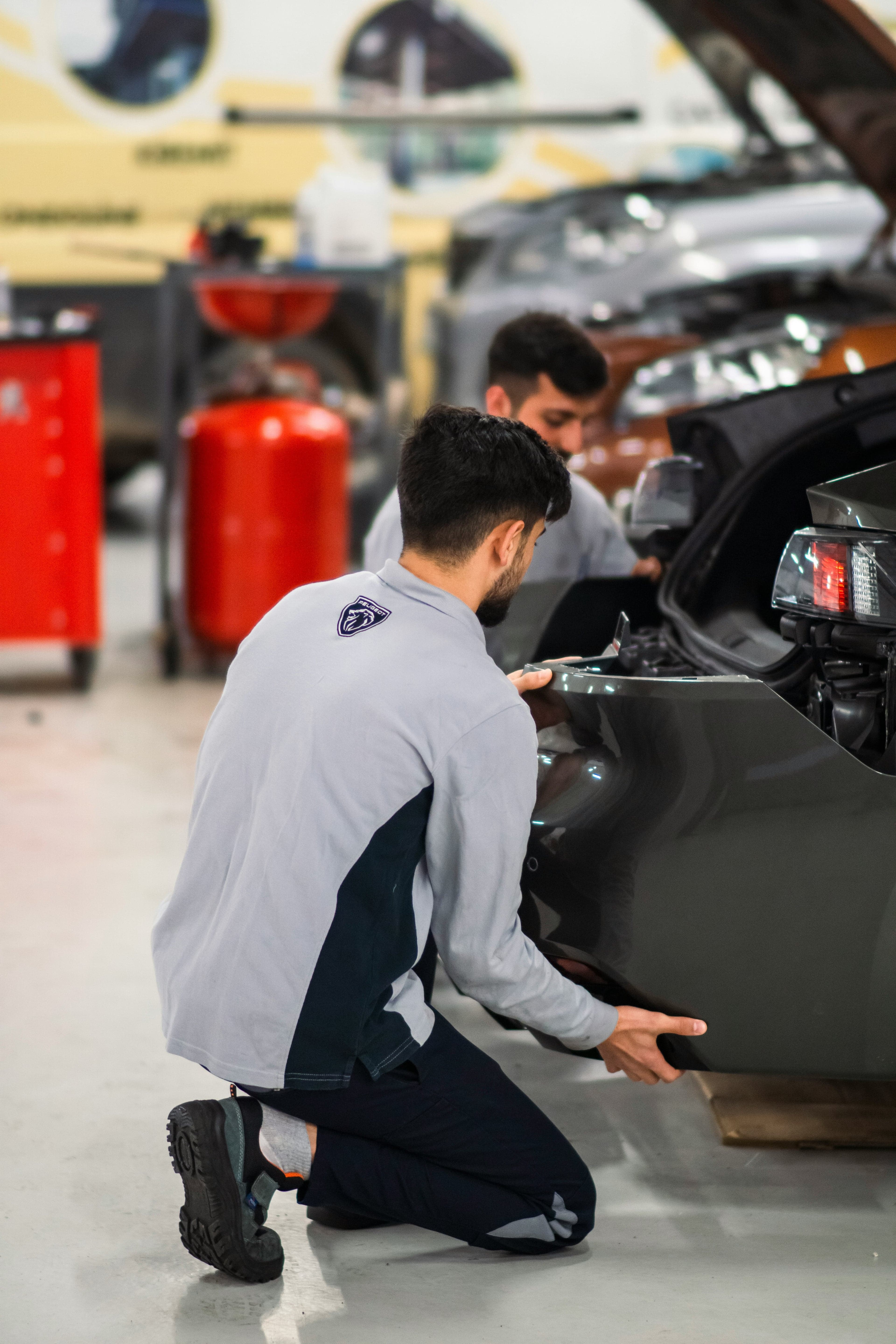 Monteurs werken aan een auto in een werkplaats.